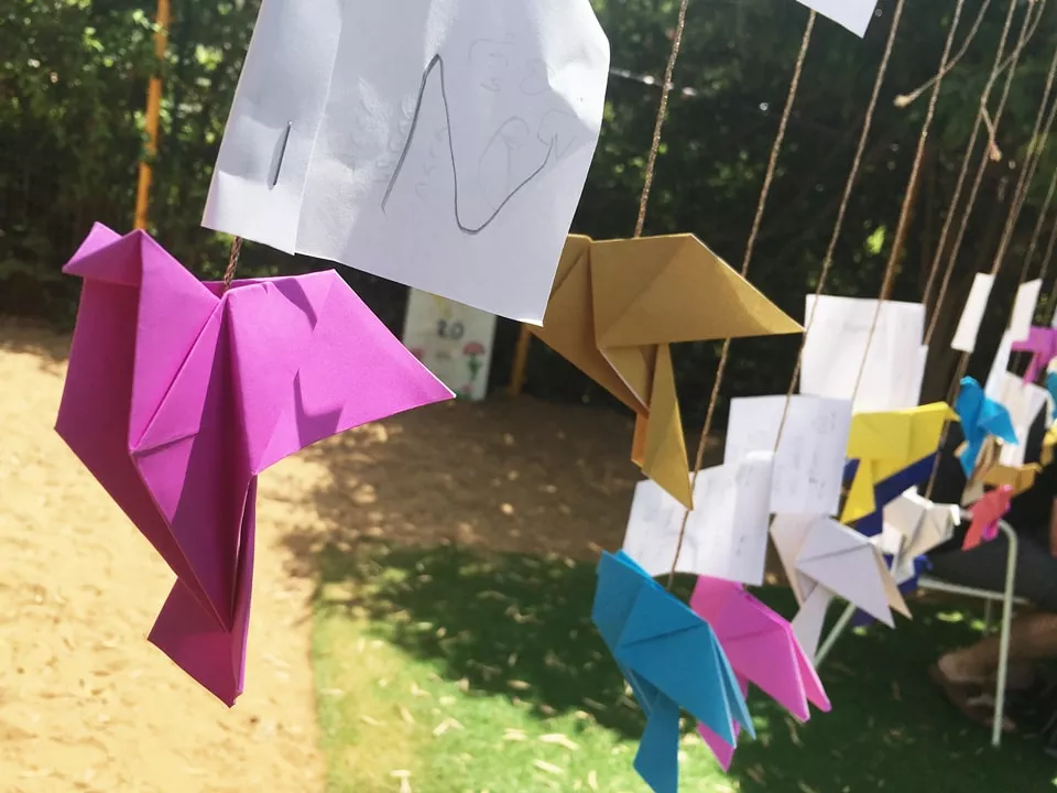 ציפורי האוריגמי עם הברכות לשנה החדשה תלויות על החוט בגן